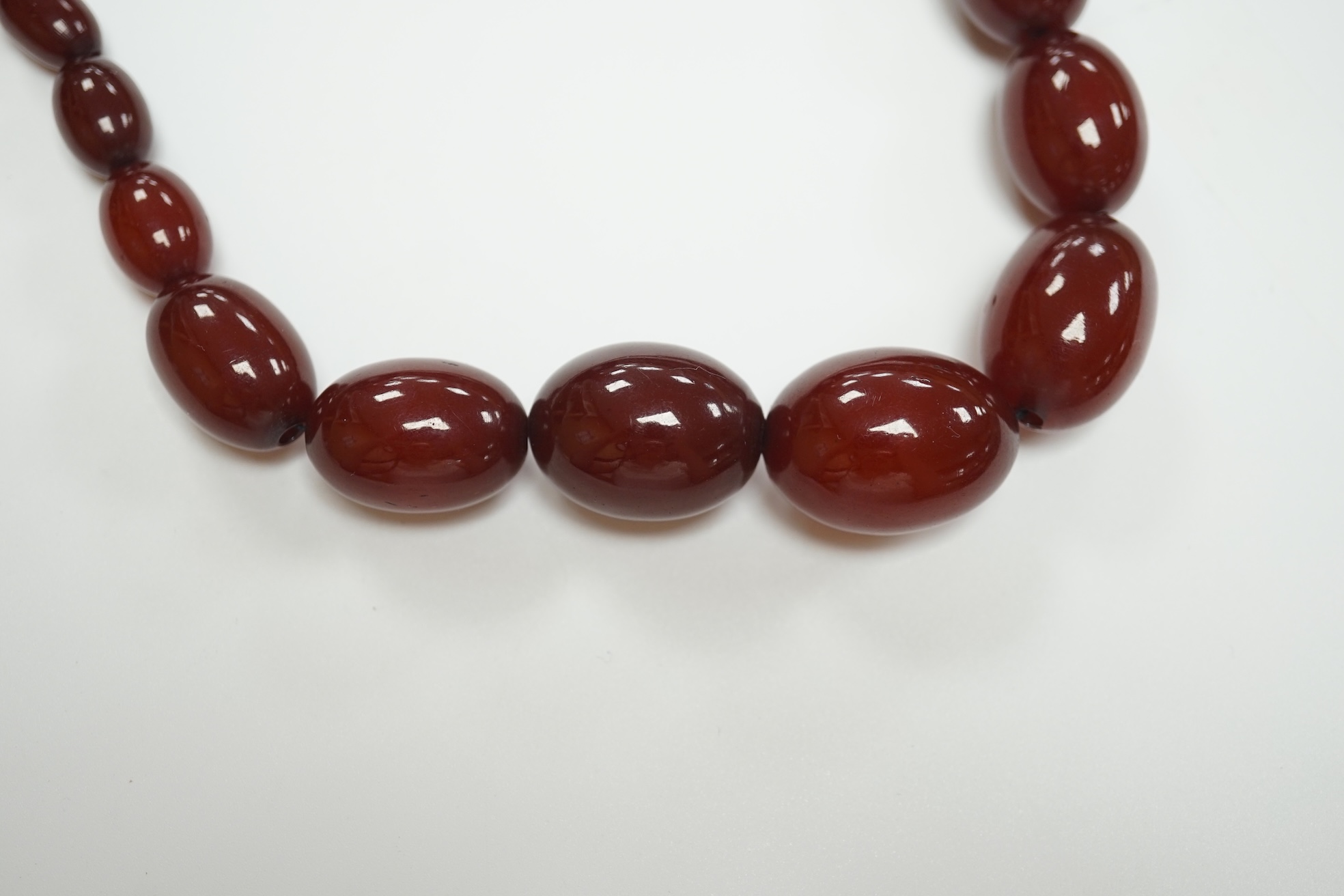 A single strand graduated oval simulated cherry amber bead necklace, 74cm, gross weight 71 grams. Condition - fair